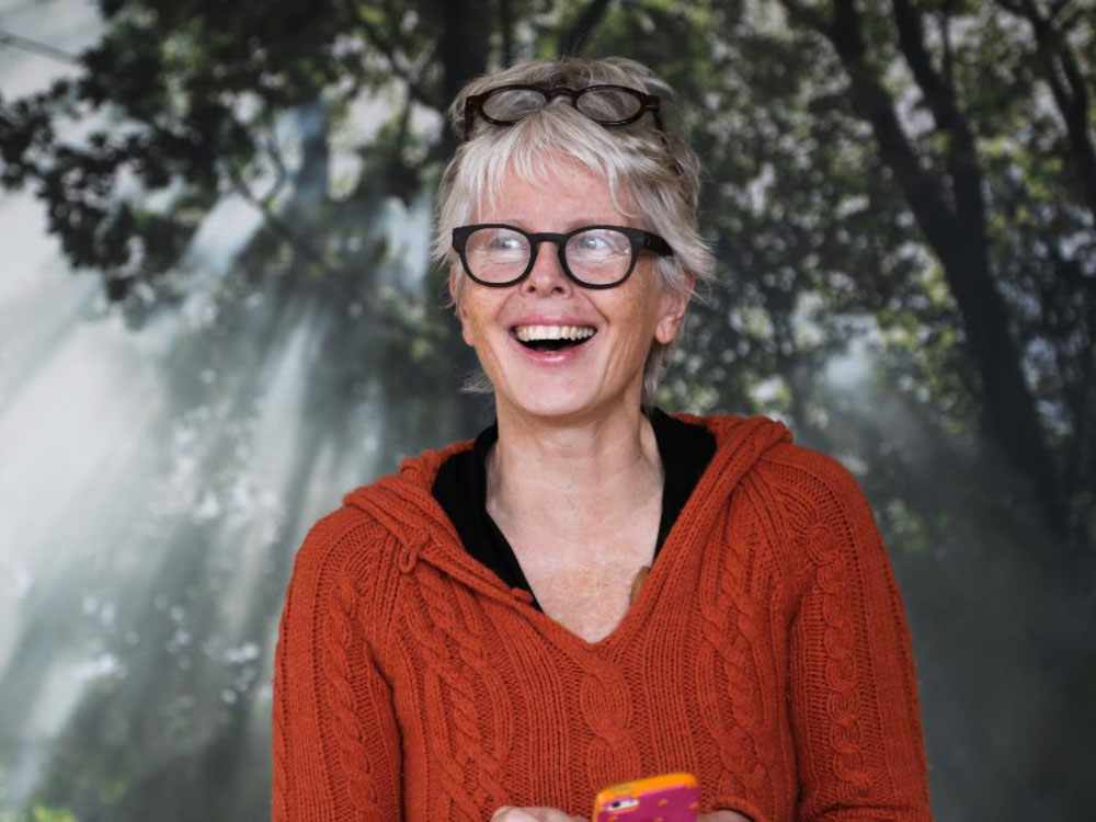 Anne Pitman smiling with two pairs of glasses on